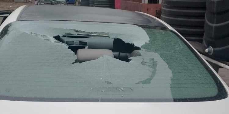 White Toyota Camry with smashed rear window parked in Festac Town, Lagos, showing vandalism damage