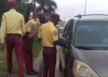 LASTMA officers directing traffic on a busy road in Lagos with the BRT corridor visible.
