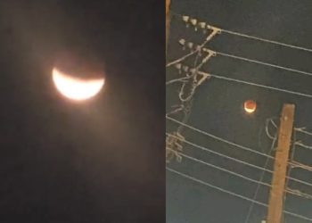 A photograph of a lunar eclipse casting a shadow on the moon, with the Lagos skyline in the foreground.