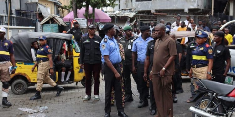 Police officers managing a crowd at a market in Lagos, Nigeria.