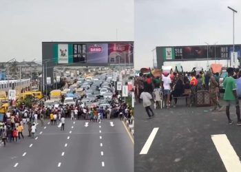 Protesters carrying signs and banners on the Third Mainland Bridge, blocking traffic.
