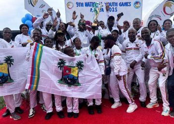 A group of jubilant young athletes from Team Lagos celebrates with their gold medals and a trophy.