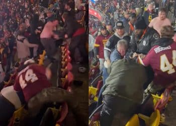 Two Washington Commanders football fans fighting in the stands at Northwest Stadium while a game is being played.