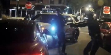 Police dashcam footage of a car collision and officer with a gun.