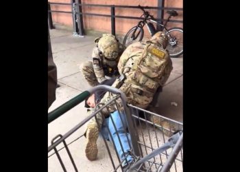 Commander Gregory K. Bovino speaking in front of federal agency logos.